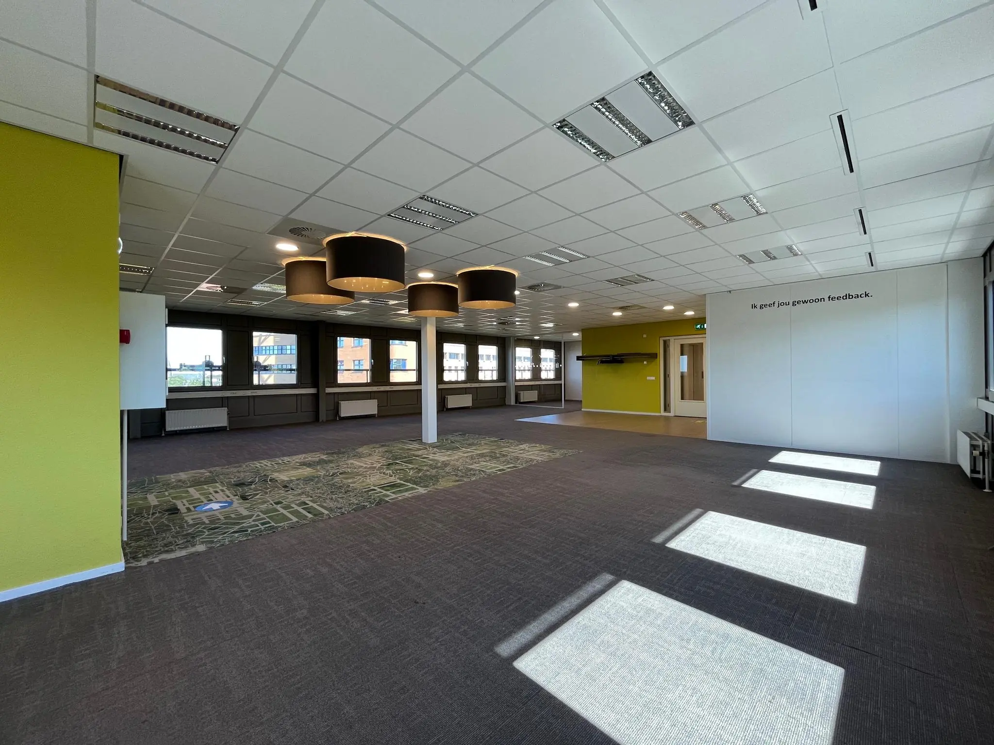 Ruime, moderne kantooretage aan de Barchman Wuytierslaan met grote ramen, tapijtvloer en opvallende hanglampen.